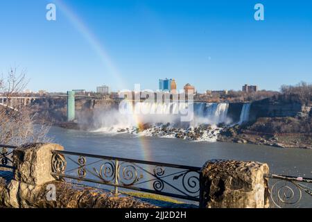 Niagara Falls, Ontario, Kanada - Dezember 13 2021 : Fallsview Trail an einem sonnigen Tag mit doppeltem Regenbogen. American Falls im Hintergrund. Stockfoto