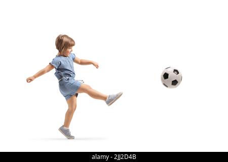 Ganzkörperaufnahme eines kleinen Mädchens, das isoliert auf weißem Hintergrund einen Fußball tritt Stockfoto