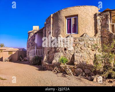 Ferienhaus in einem Beduinenlager am Meer in Ras Shitan in Oasis im Sinai, Taba Wüste mit dem Hintergrund des Meeres und der Berge. Stockfoto