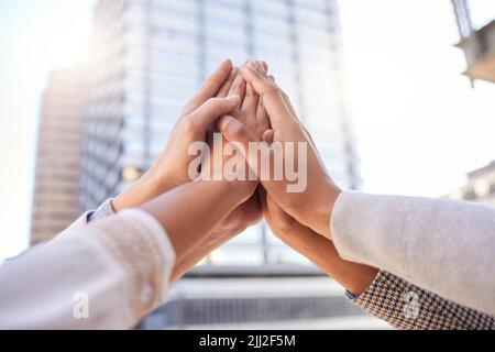 Glauben Sie an Ihre Macht, große Dinge zu erreichen. Eine Gruppe von nicht erkennbaren Geschäftsleuten, die sich gegenseitig eine hohe fünf vor einem Stadthintergrund geben. Stockfoto