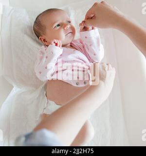 Mutter kleidet ihr neugeborenes Baby sorgfältig Stockfoto