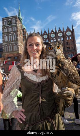 Pommern, Deutschland. 22.. Juli 2022. 22. Juli 2022, Mecklenburg-Vorpommern, Stralsund: Marie-Susann Schacht aus dem Zoo Stralsund trägt bei der Eröffnung des Wallenstein-Tages eine Adlereule an der Hand. Bis zum 24. Juli 2021 feiern die Stralsunder vor fast 400 Jahren, am 24. Juli 1628, den Sieg über die kaiserlichen Truppen unter General Albrecht von Wallenstein. Zu den Festlichkeiten gehört auch ein historischer Markt. Nach eigenen Angaben ist das Volksfest eines der größten in Norddeutschland. Foto: Stefan Sauer/dpa Quelle: dpa picture Alliance/A Stockfoto