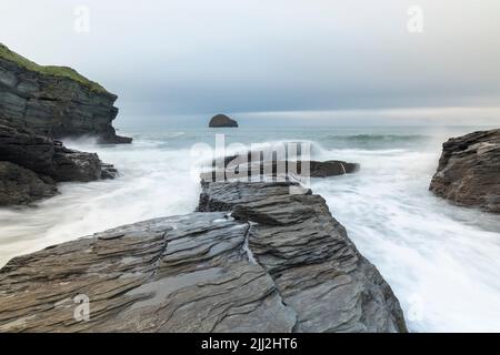 Wellen über den Felsen bei Trebarwith Strand, Cornwall, England, Großbritannien Stockfoto