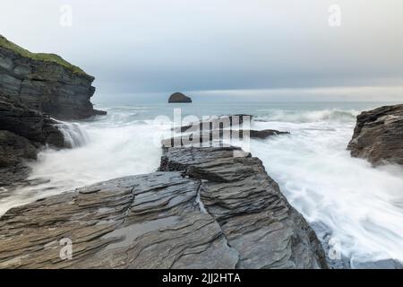 Wellen über den Felsen bei Trebarwith Strand, Cornwall, England, Großbritannien Stockfoto