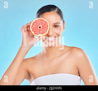 Seine Traube zu Bis zum nächsten Mal. Studioportrait einer attraktiven jungen Frau, die mit einer halben Grapefruit vor blauem Hintergrund posiert. Stockfoto