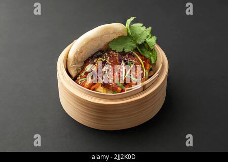 Scharfes Sandwich mit Schweinebauch, Gemüse und Koriander, serviert in einem haltbaren Behälter aus Naturmaterial Stockfoto