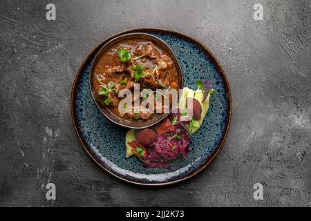 Rindereintopf, Kartoffelpüree, Rotkohl und Salat Stockfoto