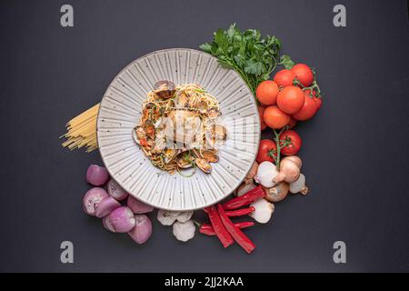 Stillleben von Weißfischen, Spaghetti und Muscheln auf der Haut gebraten. Umgeben von verschiedenen Arten von frischem Gemüse Stockfoto