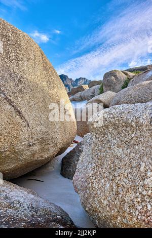 Felsenküste. Große Felsen am Strand mit einem blauen Himmel Hintergrund an einem Sommertag. Eine Landschaft von großen oder riesigen Felsbrocken am Meeresufer eines abgelegenen Stockfoto