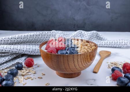 Servieren Sie eine Portion Joghurt mit Heidelbeer-Himbeere und Haferflocken in einer Holzschüssel, die Sie servieren können. Gesunde Ernährung für Diät-Konzept. Fruchtmüsl Stockfoto