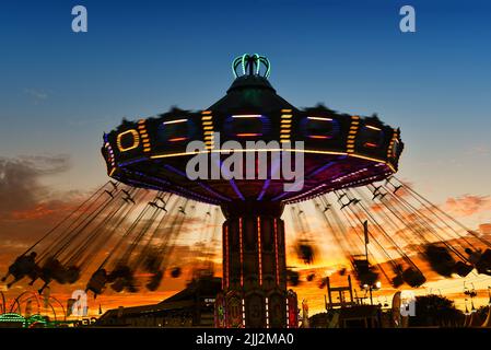 COSTA MESA, KALIFORNIEN - 20 JUL 2022: Karneval-Schaukelfahrt mit Bewegungsunschärfen auf der Orange County Fair mit einem wunderschönen Sonnenuntergangshimmel. Stockfoto