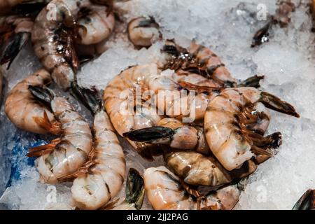 Ein Haufen großer rosa Garnelen, die auf Eis auf einem farme'r Markt oder Fischmarkt im Freien sitzen Stockfoto