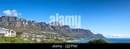 Twelve Apostles am Tafelberg in Kapstadt vor blauem Himmel an der Küste. Atemberaubendes Panorama auf einen ruhigen Vorort umgeben Stockfoto