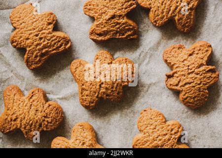 Draufsicht auf hausgemachte frische Haferflocken-Kekse in Form von Lebkuchenmännern, die auf Backpapier liegen. Hausmannskost. Süßes Essen. Stockfoto