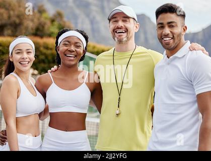 Wir gewinnen, wenn wir zusammenarbeiten. Beschnittenes Porträt von drei jungen Tennisspielern und ihrem Trainer, die draußen auf dem Platz stehen. Stockfoto