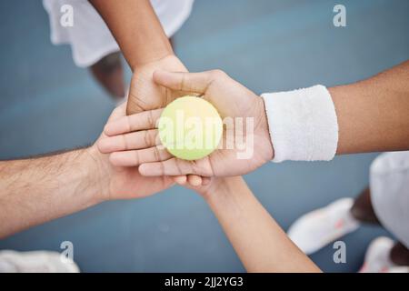 Der Ball liegt auf unserem Platz. Aus dem Hochwinkel vier unverkennbare Tennisspieler, die mit einem Ball auf dem Platz in einem Geheule stehen. Stockfoto