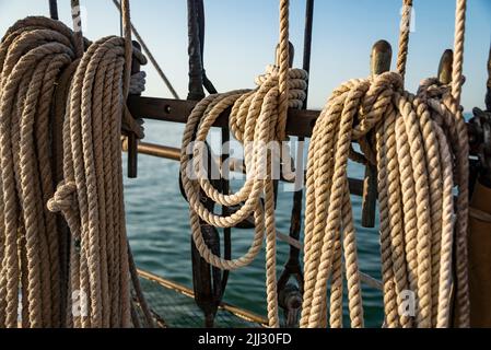 Festmacherseile, die auf einem alten Boot zusammengerollt sind. Starke geflochtene Seile zur Verankerung des Bootes im Abendlicht. Stockfoto