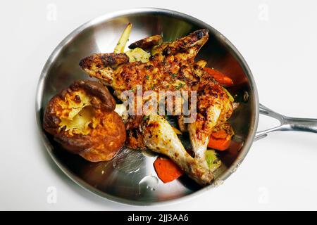 Gebratenes oder gebackenes mariniertes Baby-Huhn mit Gemüse und yorkshire-Pudding in einer Metallpfanne Stockfoto