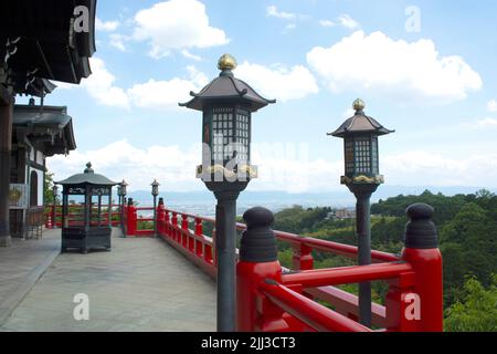 Laternen und Zaun vor dem Tempel - Schrein mit Baumlaub in Japan. Stockfoto