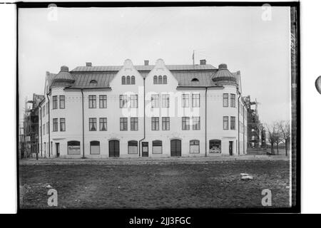 Das Eckhaus in OskaStorget, dreistöckiges Mehrfamilienhaus mit vorderen Öfen, zwei Turmhauben, kaputtes Blechdach. Stockfoto