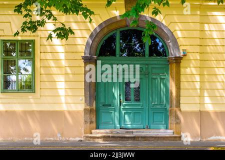 Vorderseite des alten Gebäudes (Fassade), historische Holztür (Tor). Architektur - Ungarn. Stockfoto