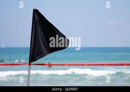 Schwarze Flagge mit einem roten Band an der Küste warnt vor gefährlicher Strömung und Wellen oder Invasion von Quallen. Stockfoto