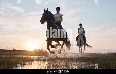Atmen Sie tief durch, entspannen Sie sich und genießen Sie den Ausritt. Zwei junge Frauen reiten zusammen. Stockfoto