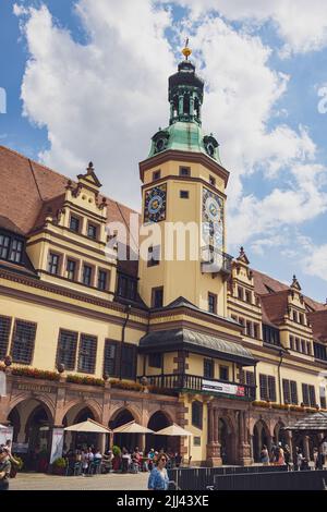 Leipzig, Deutschland - 25. Juni 2022: Das alte Rathaus am Marktplatz mit vielen Touristen auf der Straße. Blauer Himmel über der sächsischen Stadt. Das historische Stockfoto