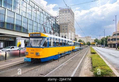 Leipzig, Deutschland - 25. Juni 2022: Leipziger Straßenbahn an der Haltestelle Augustusplatz. Die alte Straßenbahn in den Farben Blau und Gelb hält an einer Straßenbahnhaltestelle. Die Leute bekommen Stockfoto