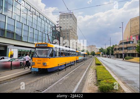Leipzig, Deutschland - 25. Juni 2022: Leipziger Straßenbahn an der Haltestelle Augustusplatz. Die alte Straßenbahn in den Farben Blau und Gelb hält an einer Straßenbahnhaltestelle. Die Leute bekommen Stockfoto