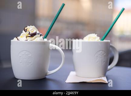 Dresden, 28. Juni 2022: Zwei Starbucks Kaffeetassen mit grünem Stroh. Das süße Getränk mit Creme auf den Getränken. Kaffeetassen auf einem Tisch, Kappe Stockfoto