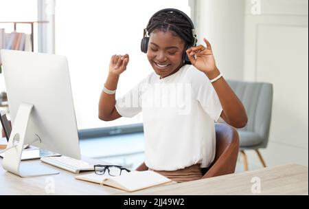 Nehmen Sie sich auch Zeit für sich selbst. eine junge Geschäftsfrau, die bei der Arbeit Musik hört. Stockfoto
