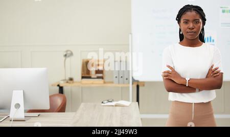 Shes hat einen Geist für das Geschäft ausgerichtet. Eine junge Geschäftsfrau, die in einem Büro bei der Arbeit steht. Stockfoto