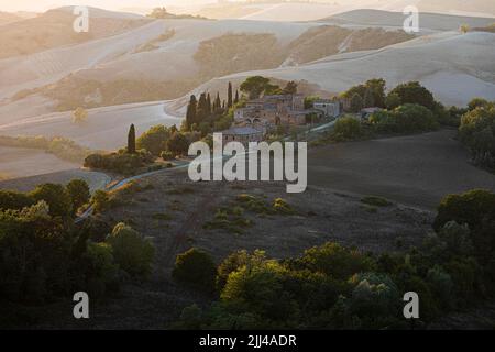 Altes Landhaus im Abendlicht, in hügeliger Landschaft der Crete Senesi, in der Nähe von Asciano, Toskana, Italien Stockfoto