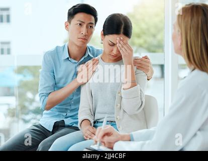 Drastische Maßnahmen. Ein reifer Arzt tröstet ein junges Paar, während er einige schlechte Nachrichten bei der Arbeit liefert. Stockfoto
