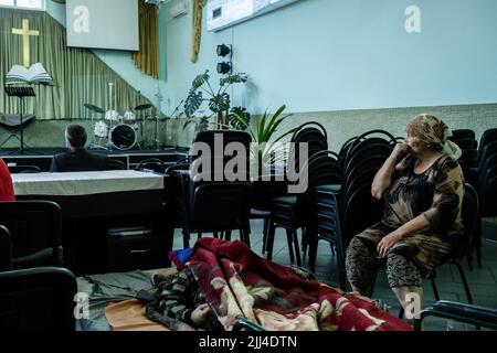 Pokorwsk, Ukraine. 15.. Juli 2022. Nach der Evakuierung mit seinem behinderten Sohn aus Bakhmut nach Pokorwsk wird eine Mutter in einer Kirche weinen sehen. Inmitten der intensivierten Kämpfe im östlichen Teil der Ukraine sind Millionen ukrainischer Familien nun aus dem immer engeren Krieg evakuiert worden, da viele von ihnen in den westlichen Teil des Landes verlagert werden. Nach Angaben der Vereinten Nationen sind seit dem russischen Einmarsch in die Ukraine mindestens 12 Millionen Menschen aus ihrer Heimat geflohen, während sieben Millionen Menschen innerhalb des Landes vertrieben werden. Kredit: SOPA Images Limited/Alamy Live Nachrichten Stockfoto
