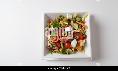 Italienische Nudelsalat Gurken, Kirschtomaten, Oliven, rote Zwiebeln, Salami, Feta-Käse und Rotini Stockfoto