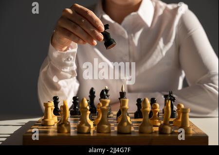 Gesichtslose kaukasische Frau im weißen Hemd, die Schach spielt. Stockfoto