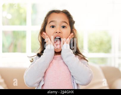 Ich kann es kaum glauben. Ein kleines Mädchen, das zu Hause schockiert aussieht. Stockfoto