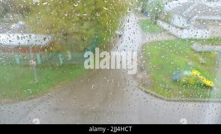 Regentropfen fallen auf stark bemalte Fenster und fließen nach unten Stockfoto