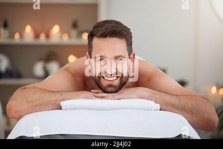 Glück ist ein Massagetag. Ein Mann entspannt sich auf einem Bett in einem Spa. Stockfoto