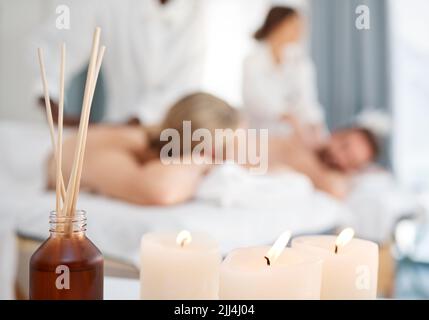 Entspannen Sie sich, wie Ihr Leben davon abhängt. Einige Kerzen und ein Paar, das im Hintergrund eine Massage in einem Spa bekommt. Stockfoto