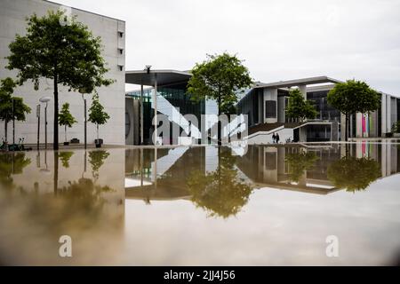 Berlin, Deutschland. 23.. Juli 2022. Das Marie-Elisabeth-Lüders-Haus (r) des Deutschen Bundestages spiegelt sich morgens in einer feuchten Steinplatte wider. Quelle: Christoph Soeder/dpa/Alamy Live News Stockfoto