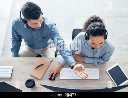 Bereitstellung geeigneter Lösungen und Alternativen. Aufnahmen von zwei Call Center-Agenten, die in einem Büro an einem Computer arbeiten. Stockfoto