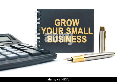 Business und Finanzen. Auf einem weißen Hintergrund befinden sich ein Rechner, ein Stift und ein schwarzes Notizbuch mit der Aufschrift - ERWEITERN SIE IHR KLEINUNTERNEHMEN Stockfoto