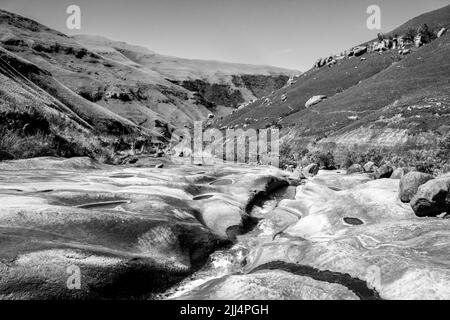 Marble Baths, ein geglätteter Sandsteinfelsenausbiss in der Injisuthi-Sektion der Drakensberg-Berge in Schwarz und Weiß Stockfoto