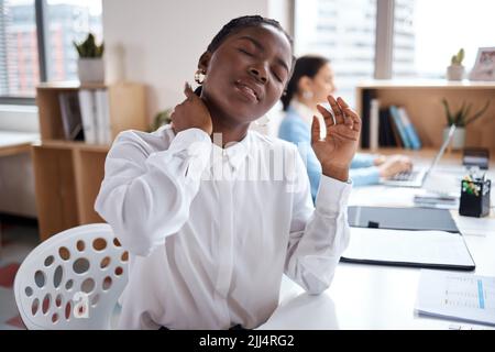 Zurückhaltung ist nicht ihr starker Anzug. Eine junge Geschäftsfrau leidet unter Nackenschmerzen, während sie an ihrem Schreibtisch in einem modernen Büro arbeitet. Stockfoto