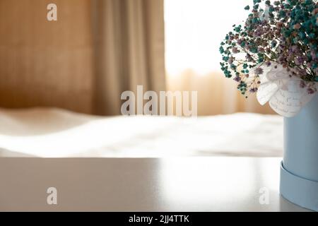 Schöner Blumenstrauß auf dem Tisch im Schlafzimmer. Platz für Text. Vase mit schönen kleinen blauen Blumen Stockfoto
