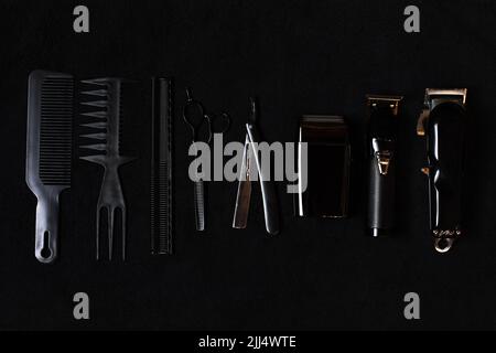 Schere, Kamm, Bürsten, Rasiermesser, elektrische Trimmer professionelle Werkzeuge von Friseur. Barbier Shop Ausrüstung Set isoliert auf schwarzem Hintergrund. Pr Stockfoto