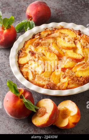 Nahaufnahme von frischen Bio-Pfirsichen und köstlichem Pfirsich-Cobbler in einem Keramikgericht auf dem Tisch gebacken. Vertikal Stockfoto